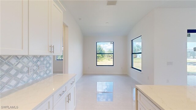 kitchen with white cabinetry, light stone countertops, and decorative backsplash