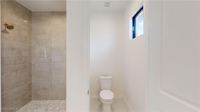 bathroom featuring tiled shower and toilet