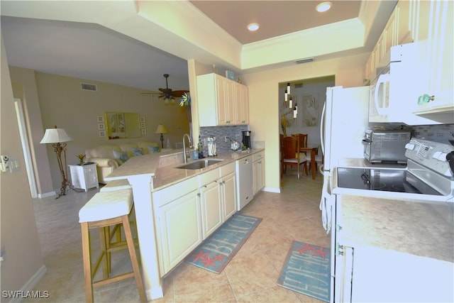 kitchen with white appliances, sink, ceiling fan, kitchen peninsula, and a breakfast bar area