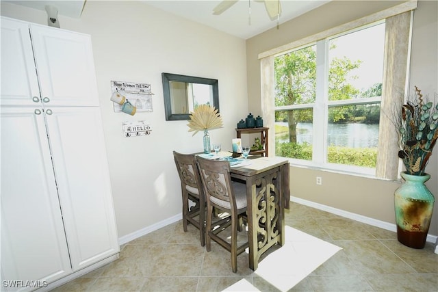 dining room featuring a water view, a wealth of natural light, ceiling fan, and light tile patterned floors