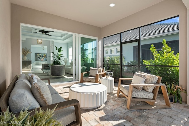 sunroom with a raised ceiling and a ceiling fan