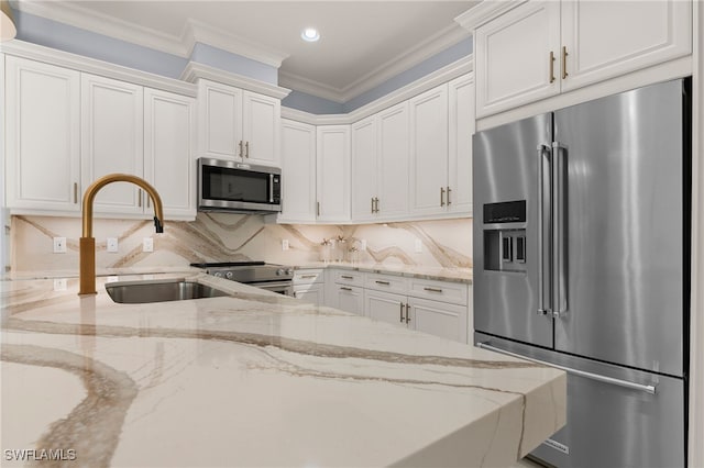 kitchen with white cabinetry, light stone counters, stainless steel appliances, and ornamental molding