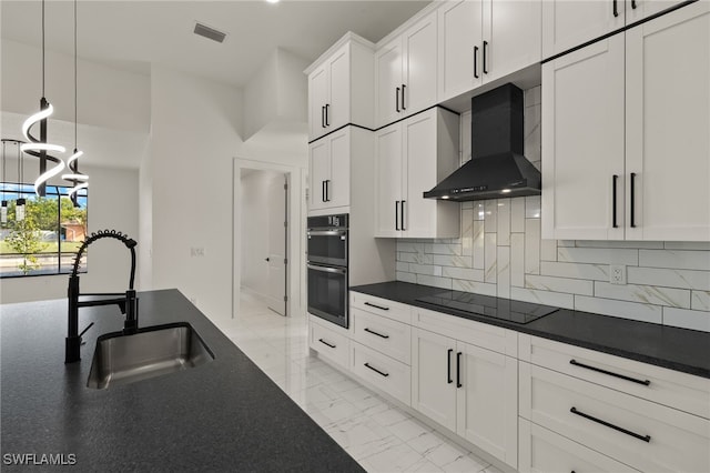 kitchen with black appliances, sink, wall chimney exhaust hood, decorative backsplash, and white cabinetry