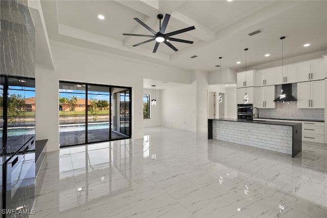 kitchen featuring wall chimney exhaust hood, coffered ceiling, white cabinetry, tasteful backsplash, and hanging light fixtures