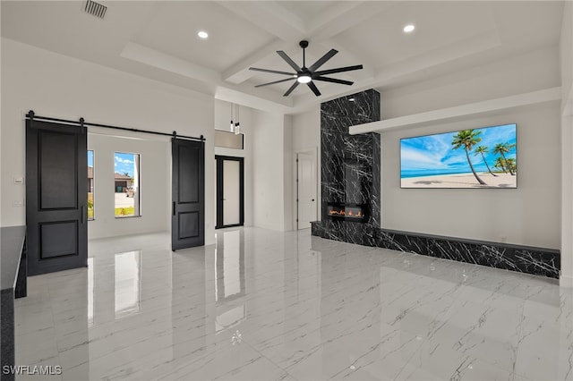 unfurnished living room with ceiling fan, coffered ceiling, a barn door, beamed ceiling, and a fireplace