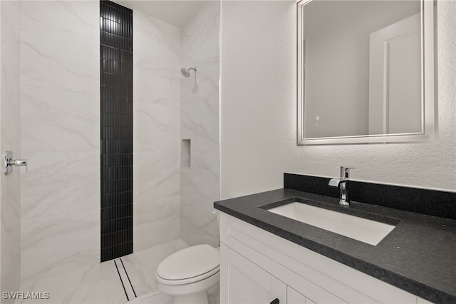 bathroom featuring tiled shower, vanity, and toilet