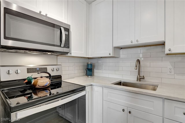 kitchen featuring backsplash, sink, white cabinets, and stainless steel appliances