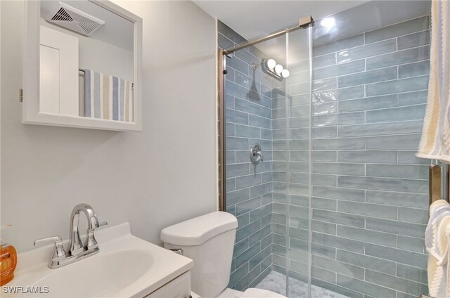 bathroom with vanity, toilet, and tiled shower