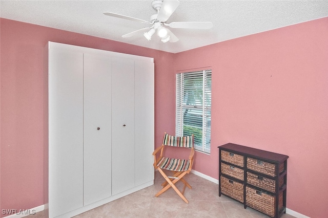 living area featuring ceiling fan and a textured ceiling