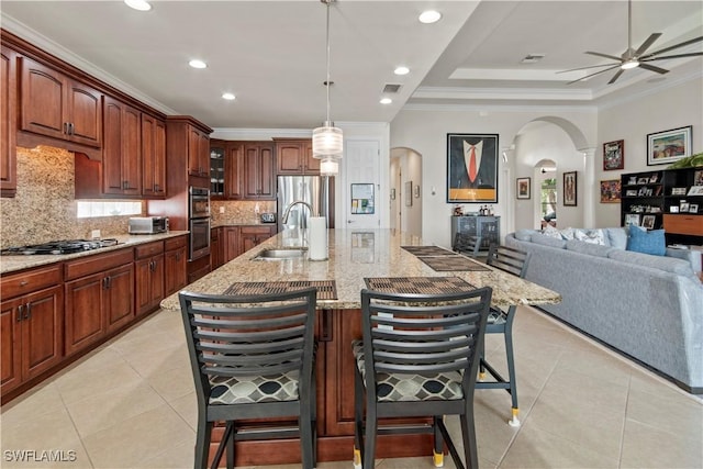 kitchen with decorative light fixtures, a kitchen bar, sink, a tray ceiling, and appliances with stainless steel finishes