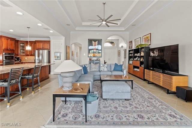 tiled living room with ceiling fan, crown molding, and a tray ceiling