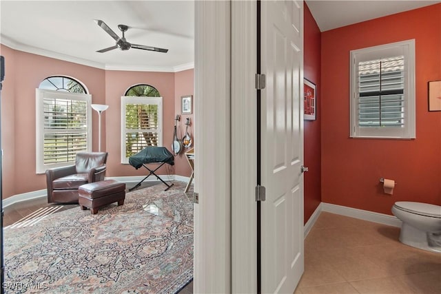 living area featuring ceiling fan, light tile patterned floors, and crown molding