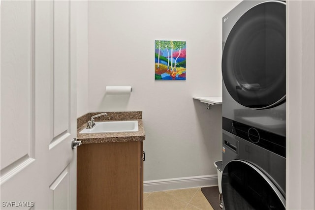 washroom with sink, light tile patterned floors, and stacked washing maching and dryer