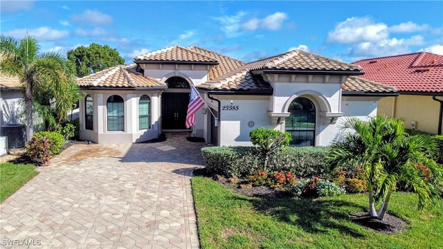 mediterranean / spanish house with cooling unit and a front lawn