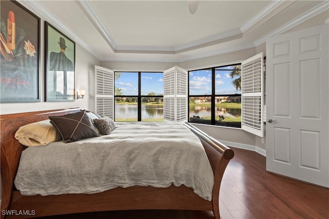 bedroom featuring hardwood / wood-style floors, crown molding, a raised ceiling, and a water view