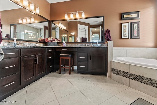 bathroom with tile patterned flooring, tiled tub, and vanity