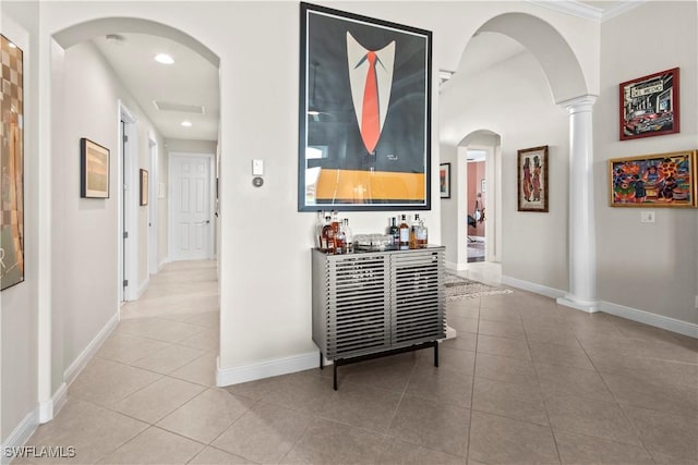 corridor with light tile patterned floors, crown molding, and ornate columns