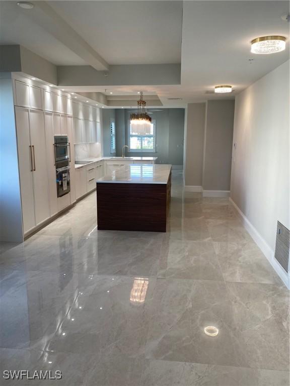 kitchen featuring a notable chandelier, white cabinetry, double wall oven, and decorative light fixtures