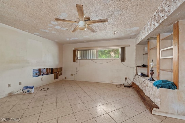 empty room featuring ceiling fan, light tile patterned floors, and a textured ceiling