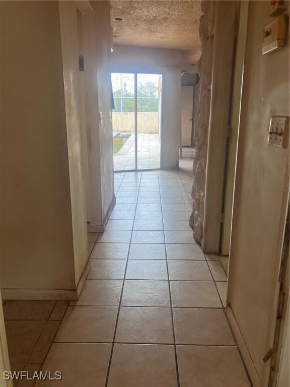 hallway with light tile patterned flooring and a textured ceiling