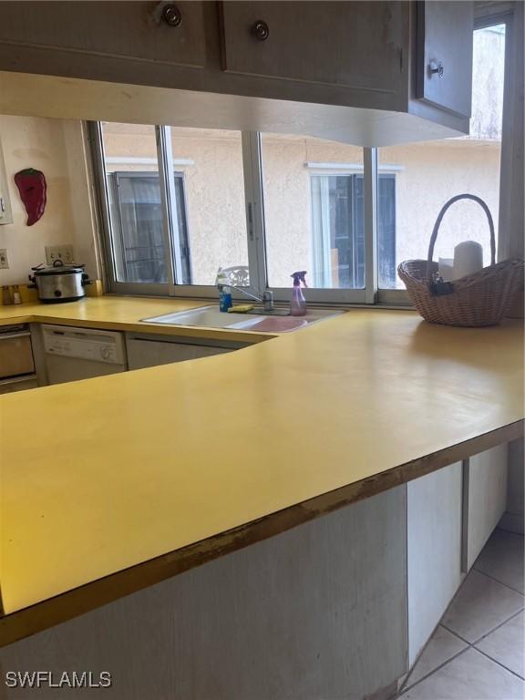 kitchen featuring white dishwasher, sink, and light tile patterned flooring