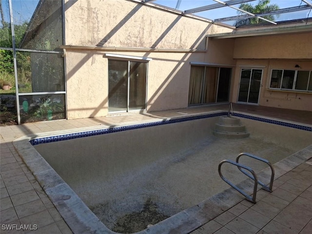 view of pool featuring glass enclosure and a patio area