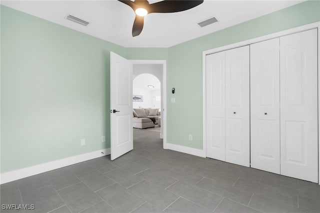 unfurnished bedroom with tile patterned floors, ceiling fan, and a closet