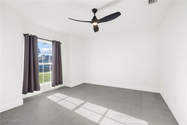 unfurnished room with dark tile patterned flooring, ceiling fan, and a healthy amount of sunlight