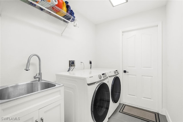 laundry room with cabinets, light tile patterned floors, washing machine and dryer, and sink