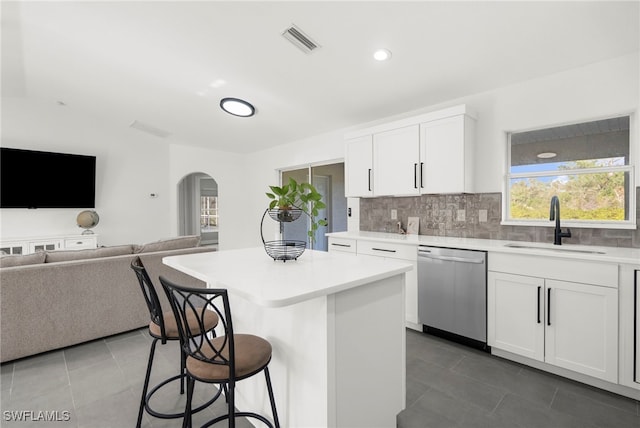 kitchen featuring a center island, a kitchen breakfast bar, sink, stainless steel dishwasher, and white cabinetry