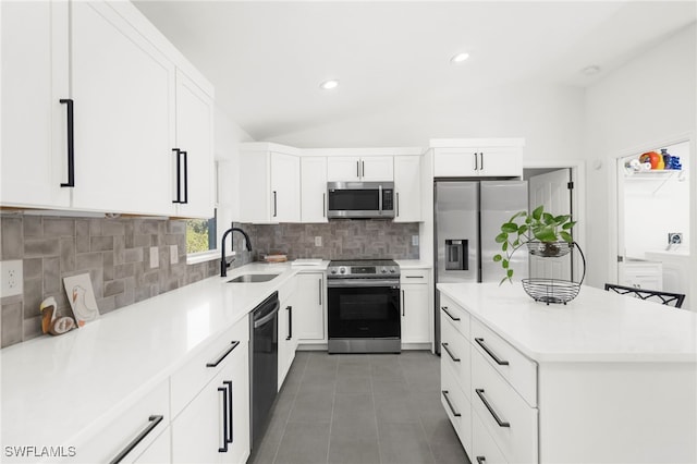 kitchen with white cabinetry, sink, stainless steel appliances, backsplash, and lofted ceiling