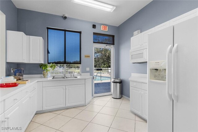 kitchen featuring sink, white cabinets, light tile patterned flooring, and white appliances