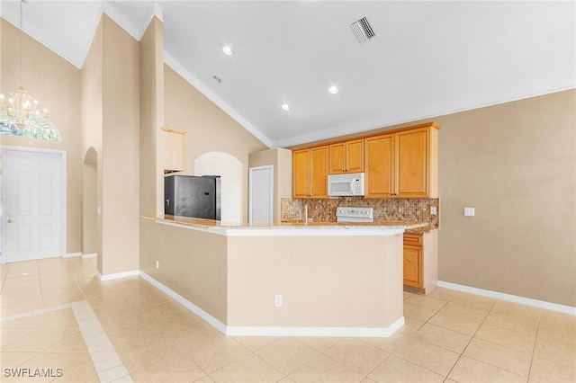 kitchen featuring stainless steel refrigerator, light stone countertops, tasteful backsplash, kitchen peninsula, and light tile patterned floors