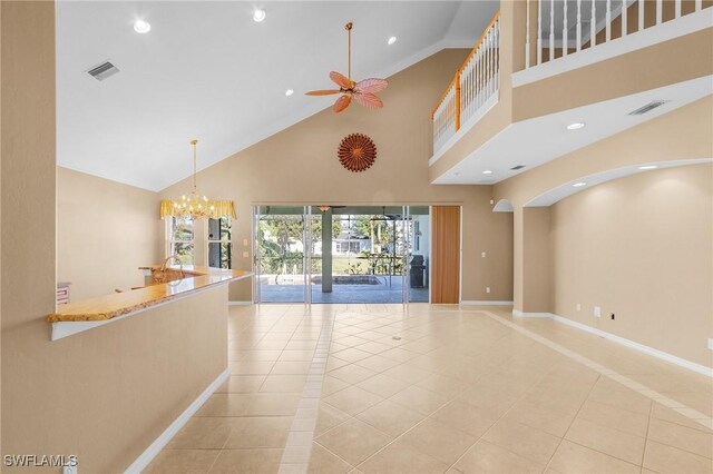 unfurnished living room featuring ceiling fan with notable chandelier, light tile patterned floors, and high vaulted ceiling