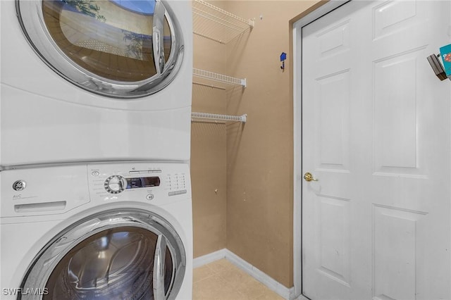 laundry room featuring light tile patterned floors and stacked washer and dryer