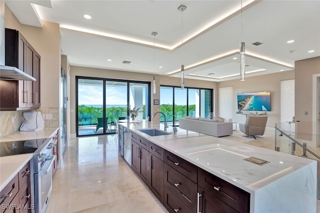 kitchen with high end range, light stone countertops, sink, hanging light fixtures, and plenty of natural light