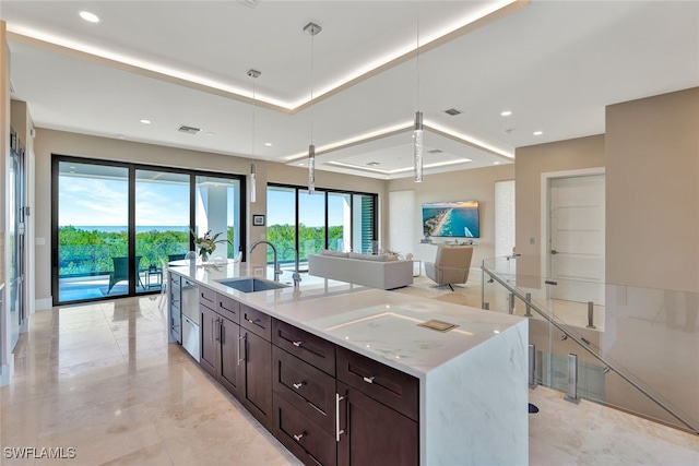 kitchen featuring light stone countertops, a wealth of natural light, hanging light fixtures, and sink