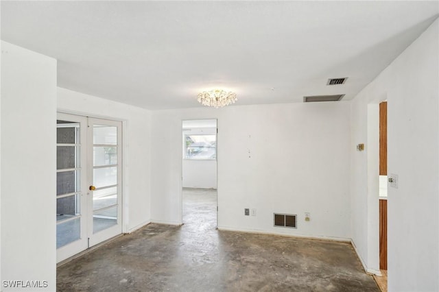 unfurnished room featuring french doors, concrete floors, and a notable chandelier