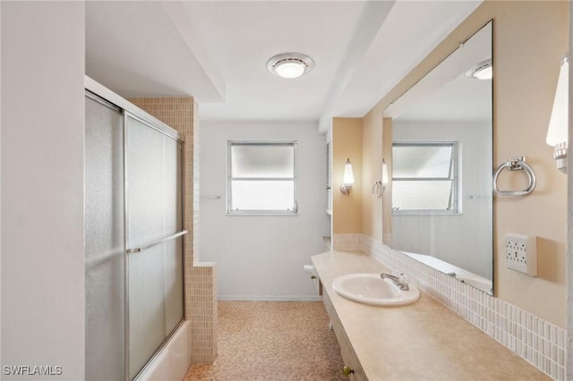 bathroom with decorative backsplash, plenty of natural light, vanity, and combined bath / shower with glass door