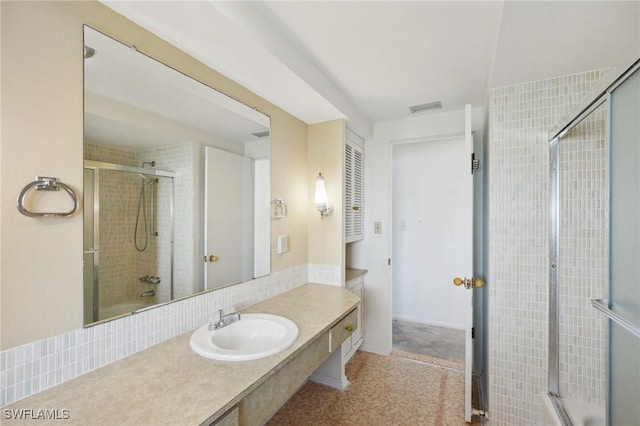 bathroom featuring vanity, tasteful backsplash, and bath / shower combo with glass door