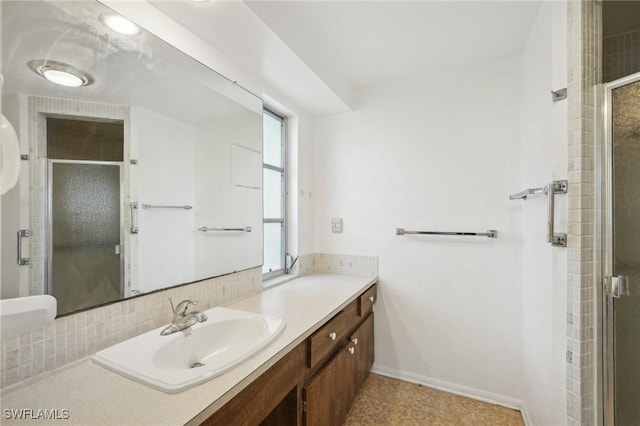 bathroom featuring vanity, a shower with shower door, and backsplash