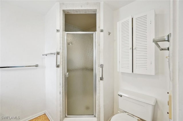 bathroom featuring toilet and a shower with door