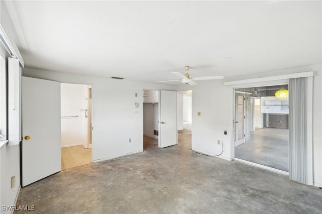 unfurnished bedroom featuring concrete flooring, a closet, ceiling fan, and ensuite bathroom