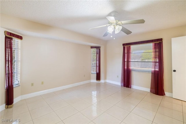 spare room with ceiling fan, light tile patterned floors, and a textured ceiling