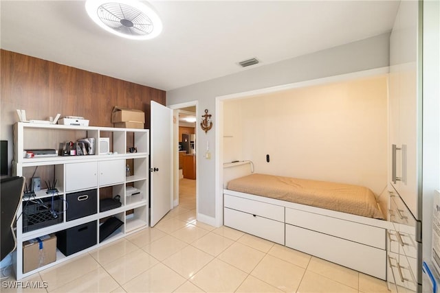 bedroom with light tile patterned floors and wooden walls