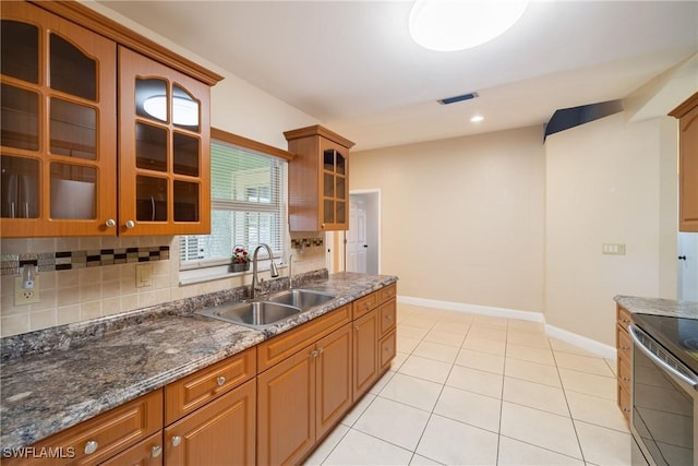 kitchen featuring tasteful backsplash, dark stone counters, sink, light tile patterned floors, and electric range