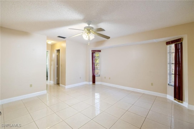 tiled empty room featuring ceiling fan and a textured ceiling