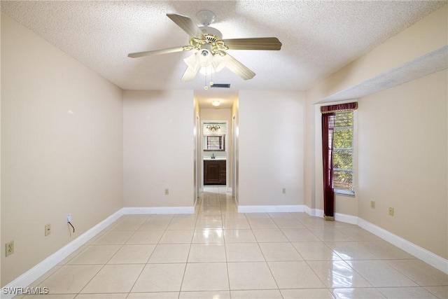 tiled empty room with ceiling fan and a textured ceiling