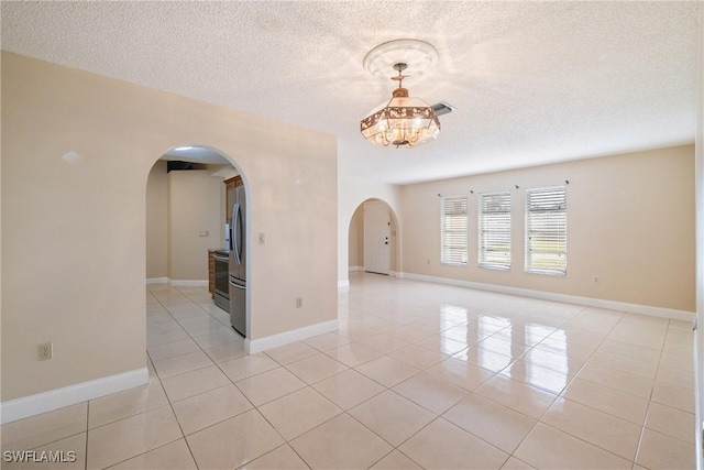 tiled empty room featuring a textured ceiling