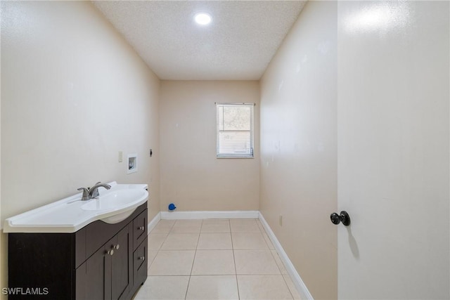 washroom with electric dryer hookup, cabinets, sink, washer hookup, and a textured ceiling